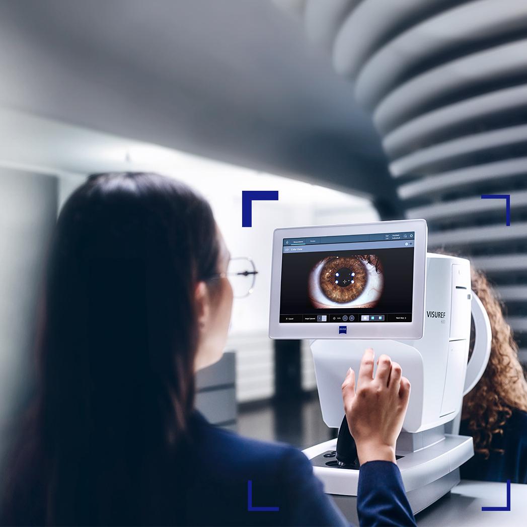 Жінка-оптик дивиться на екран приладу ZEISS VISUREF 600, на якому відображається зображення ока.