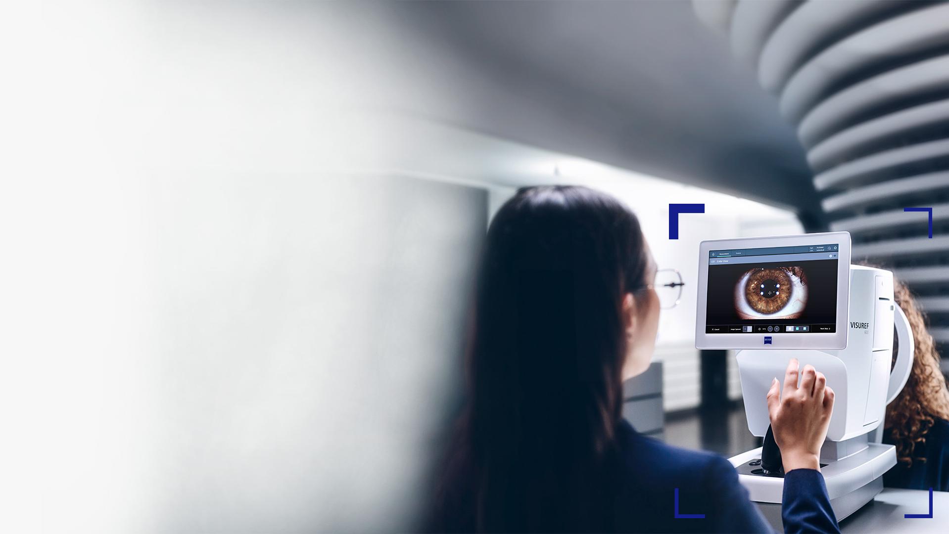 Жінка-оптик дивиться на екран приладу ZEISS VISUREF 600, на якому відображається зображення ока.