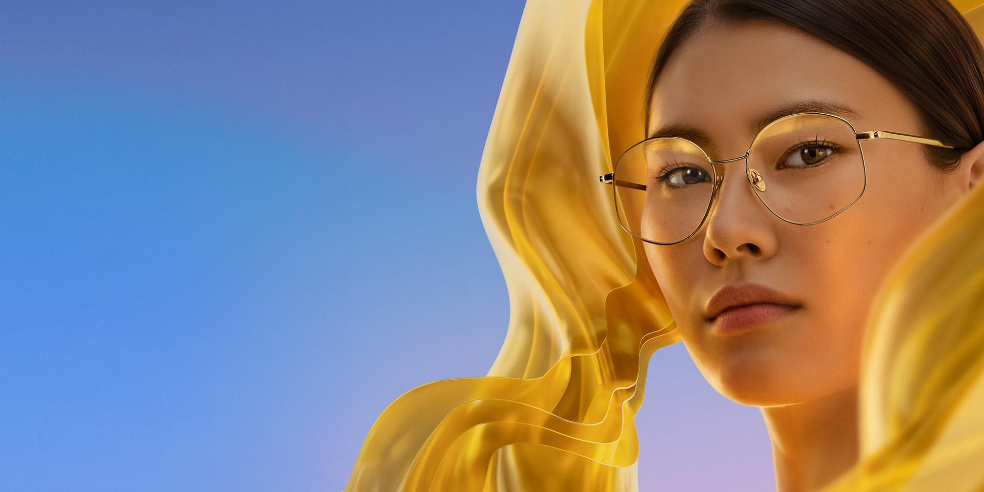 Жінка в прозорих окулярах із покриттям ZEISS DuraVision Gold UV, що надає лінзам делікатного, але виразного золотистого відблиску.