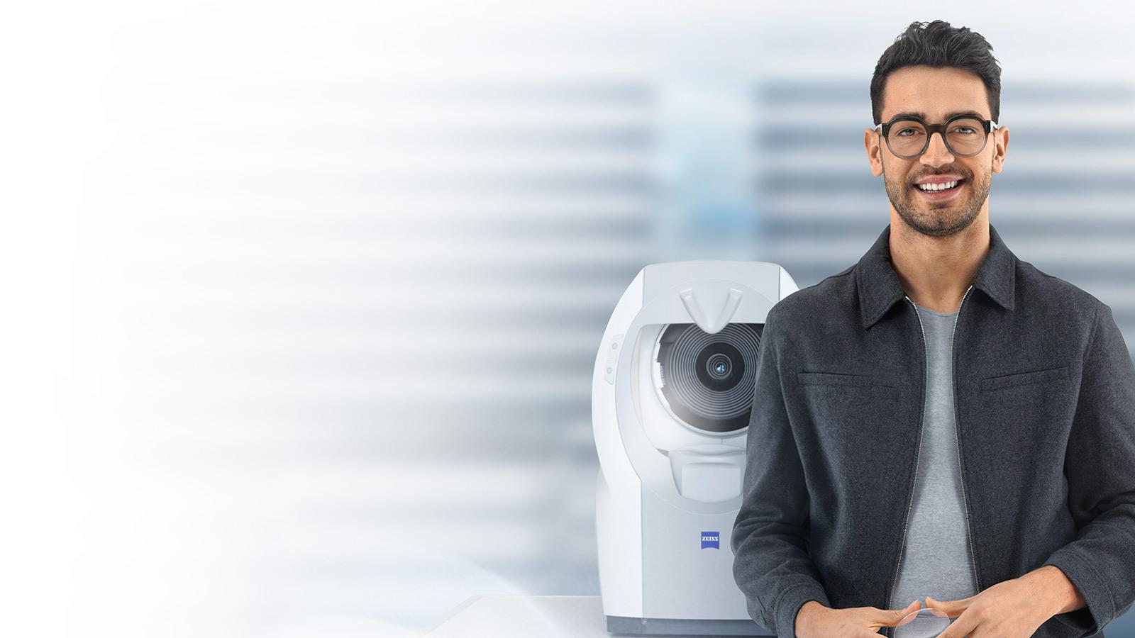 Молодий чоловік із коротким темним волоссям у лінзах ZEISS посміхається на камеру. На тлі – ZEISS i.Profiler plus.