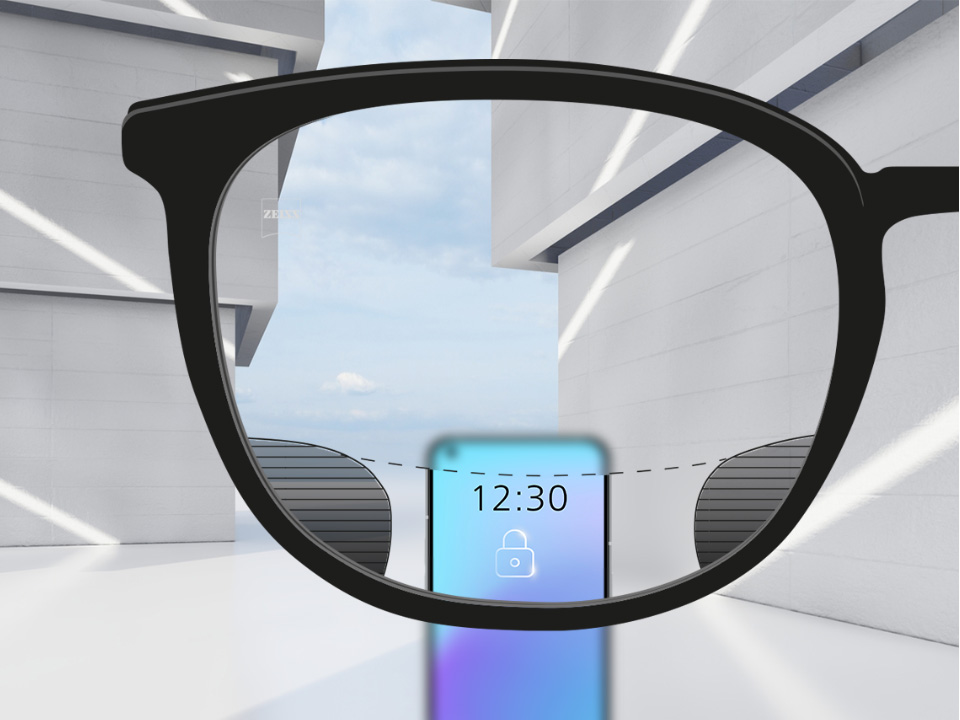 Зображення при погляді крізь лінзи ZEISS Digital SmartLife зі смартфоном; зображення повністю чітке у верхній та нижній частинах лінзи й має невеликі розмиті ділянки зліва та справа.